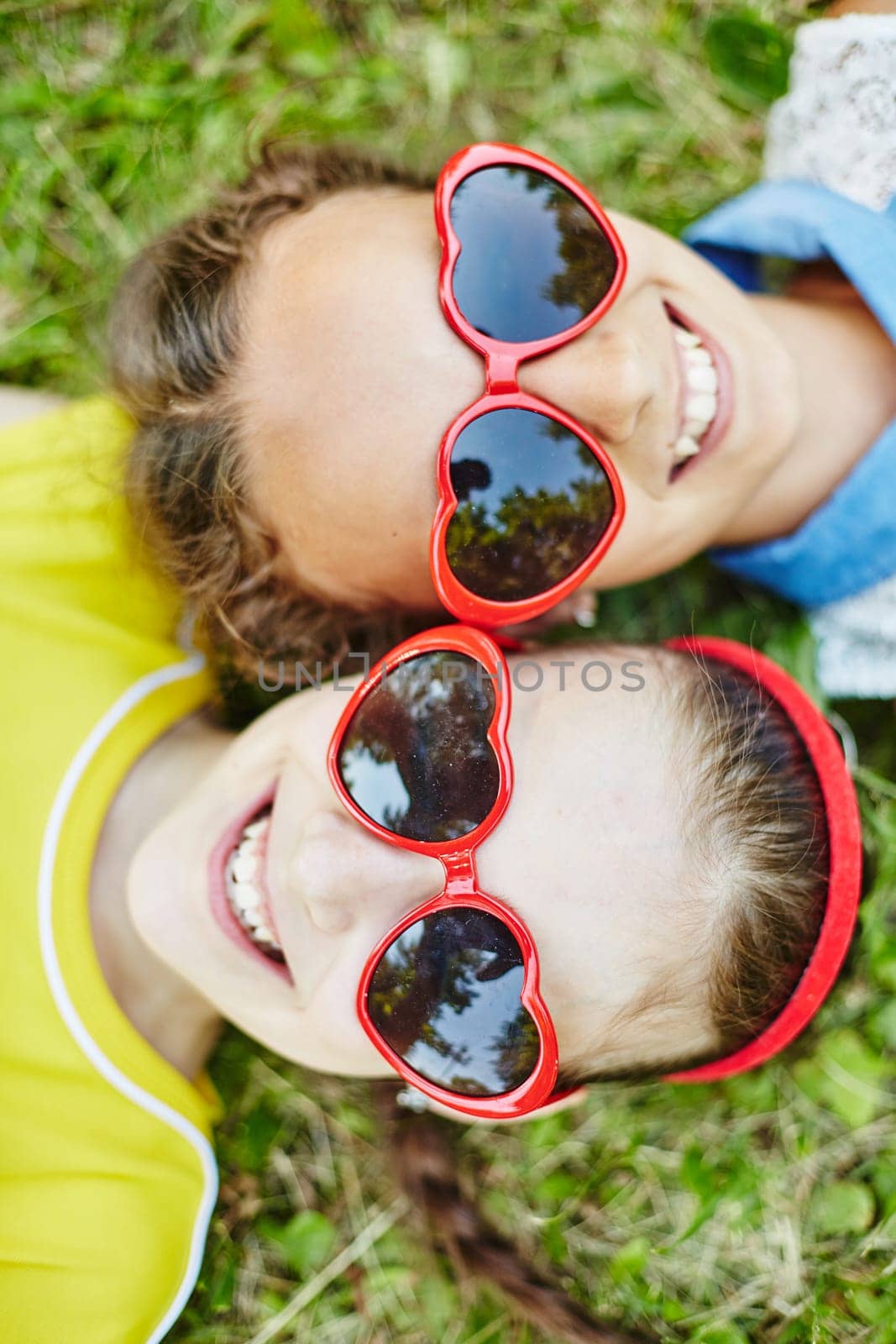 Friendly girls in sunglasses relaxing on grass