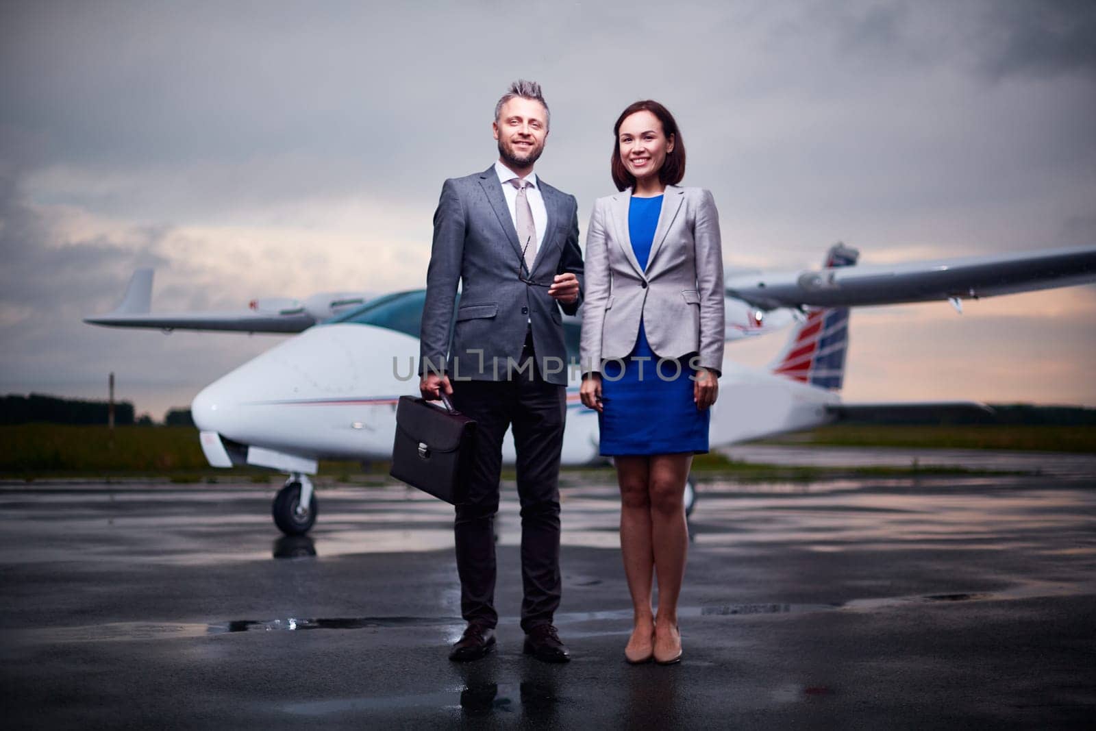 Elegant business leaders standing on arrival area on overcast evening
