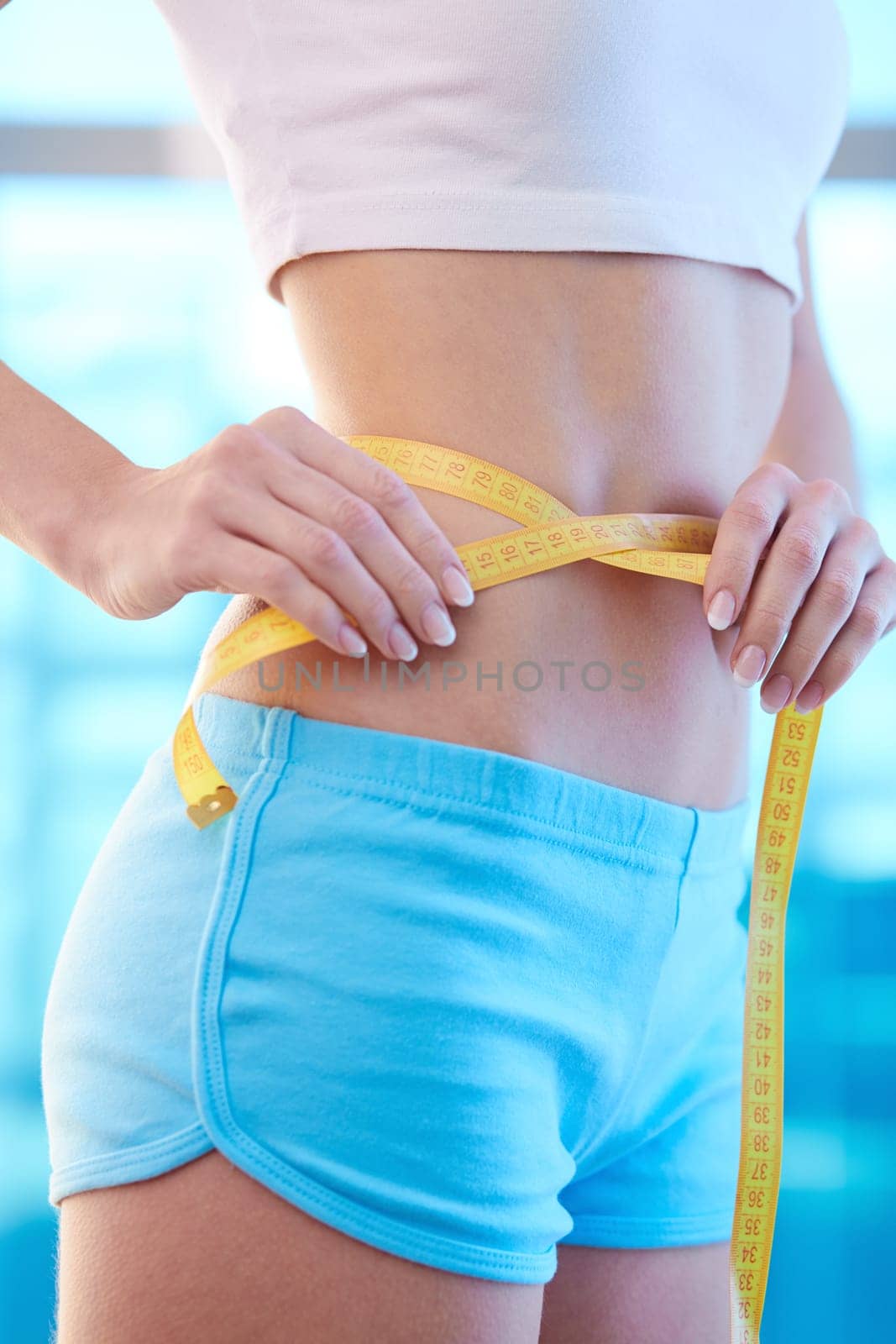 Slim female with perfect shape measuring her waist