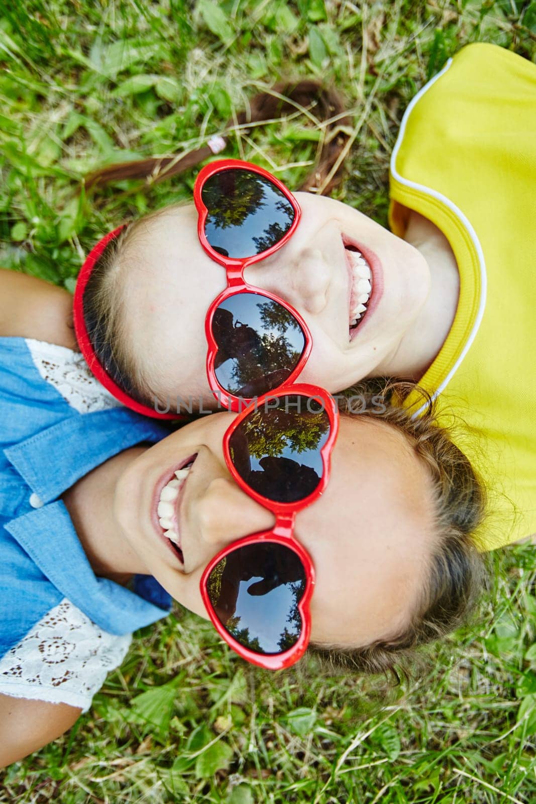 Happy girls in sunglasses looking at camera with smiles while relaxing outdoors