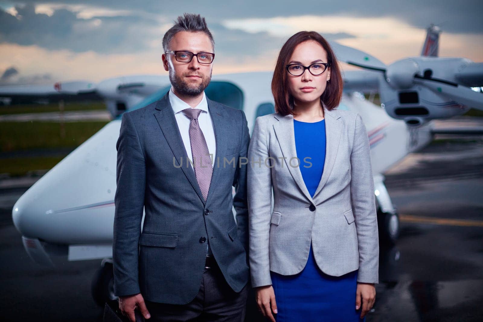 Two businesspeople in formalwear looking at camera outdoors