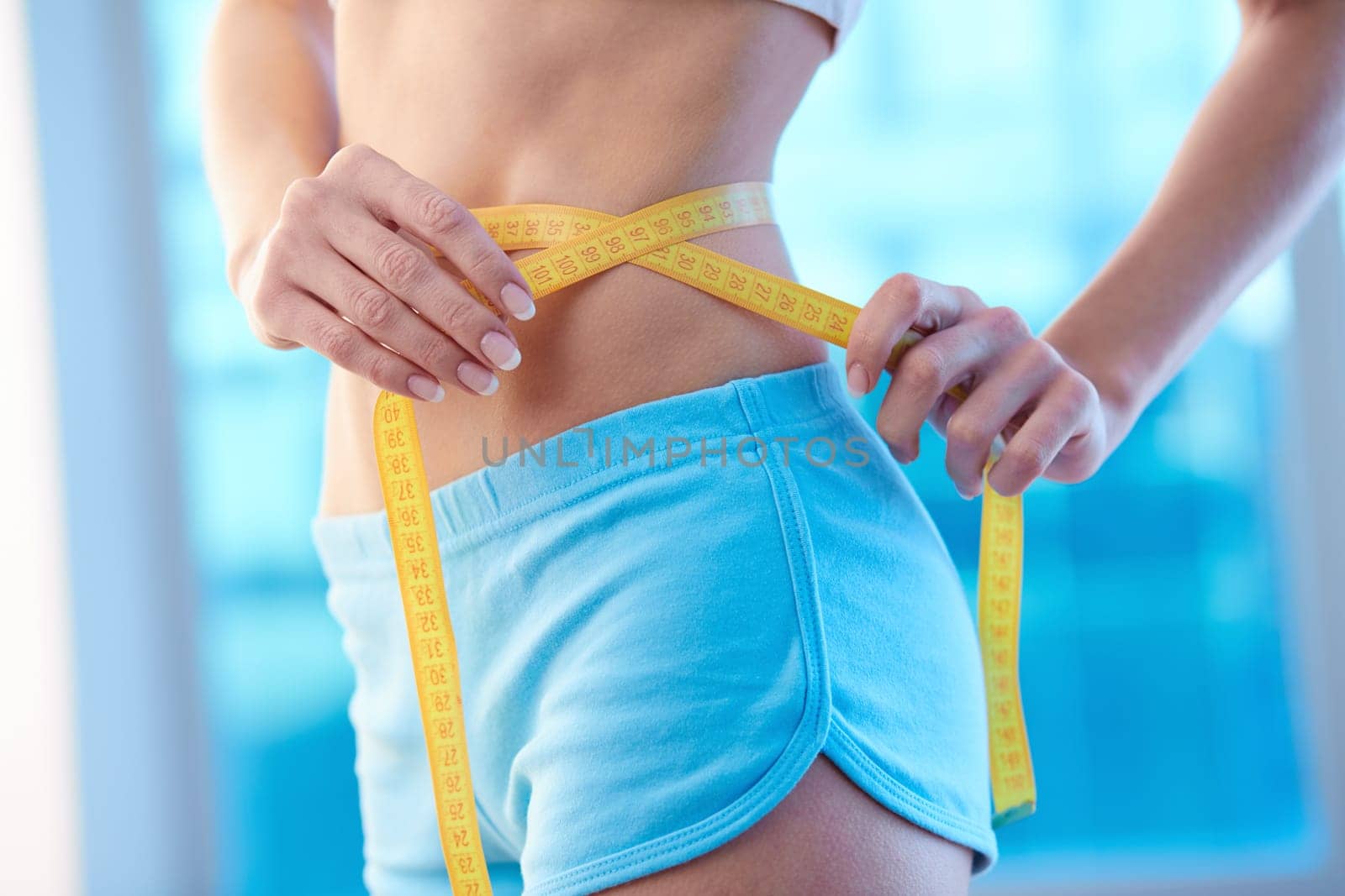 Waist of slim female with measuring tape around