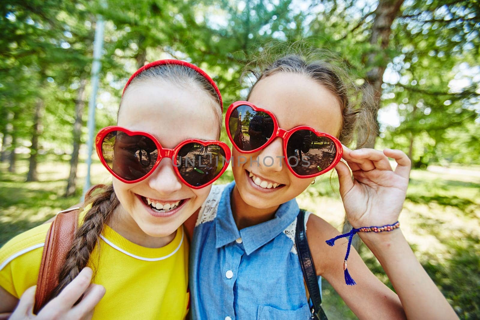 Friendly girls in sunglasses looking at camera outdoors