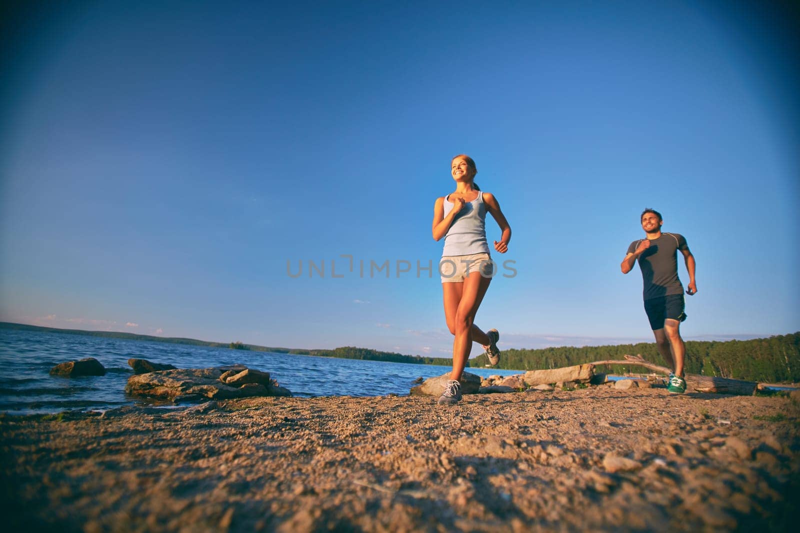 Young man and woman running along sea shore