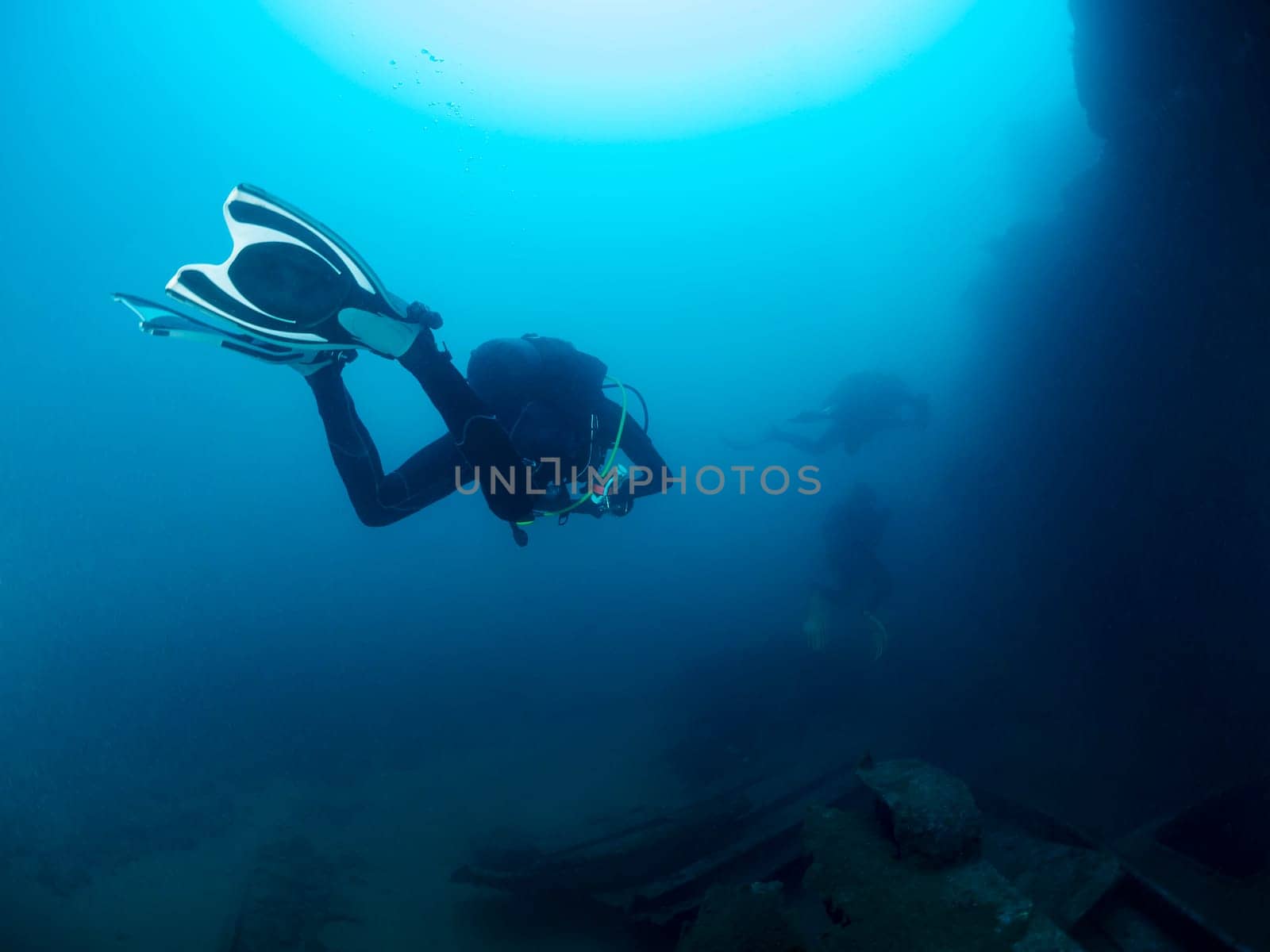 scuba diver diving a wreck in deep blue sea, the image has a moody and mysterious atmosphere