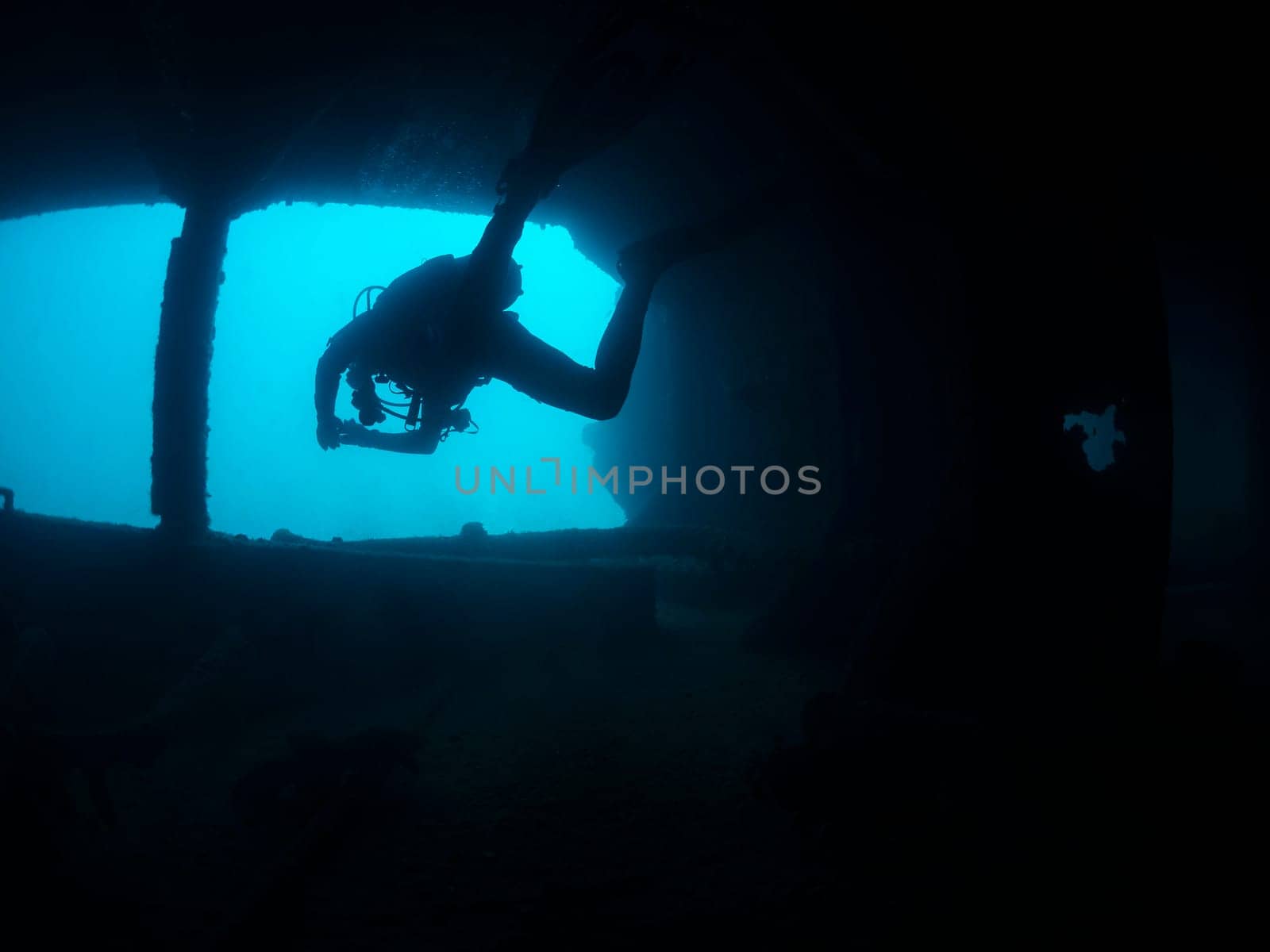 unrecognizable scuba diver diving in the dark water of a shipwreck, the image has a moody and mysterious atmosphere, as the man is the only visible figure in the scene