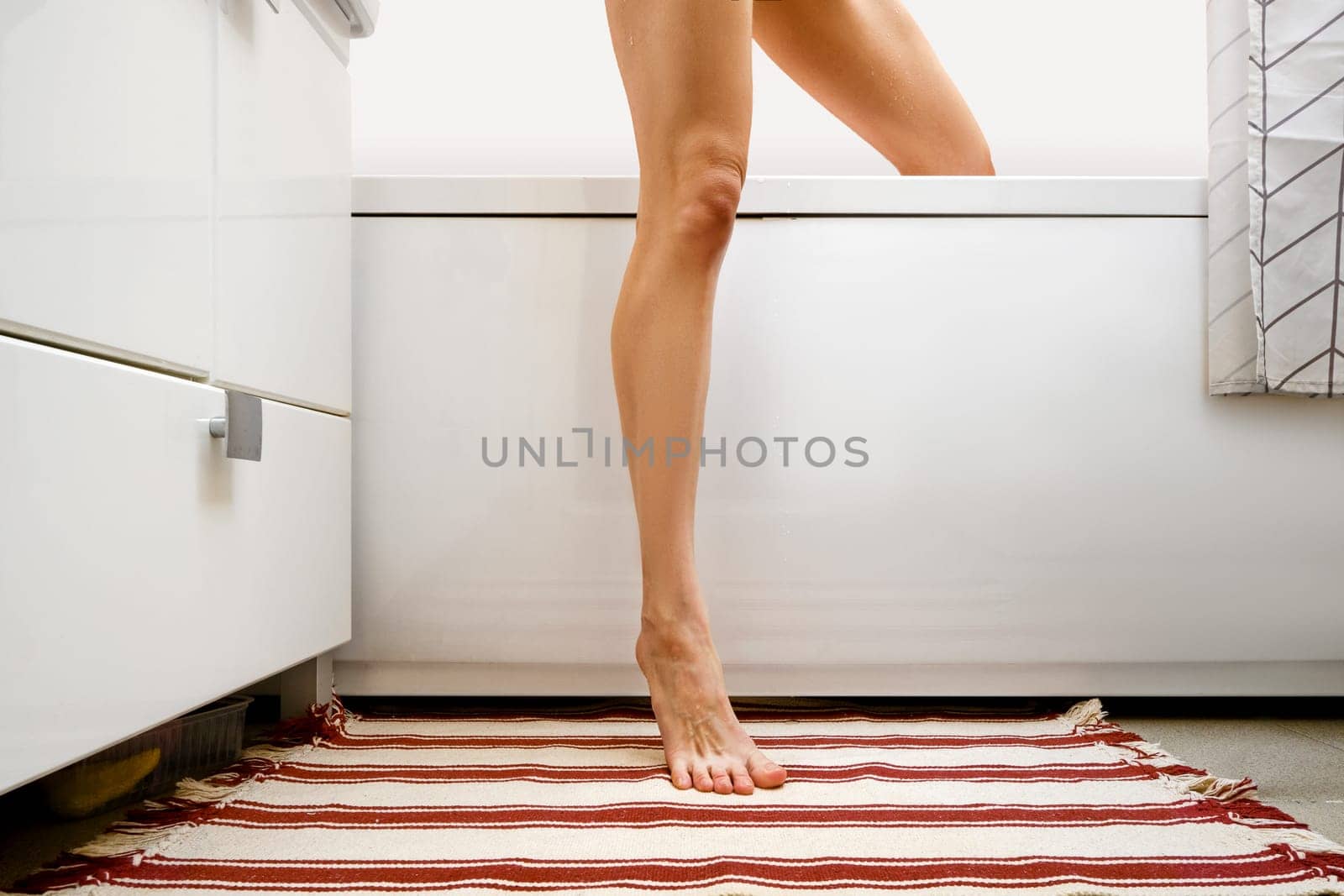 Unrecognizable woman coming out of bathtub after shower