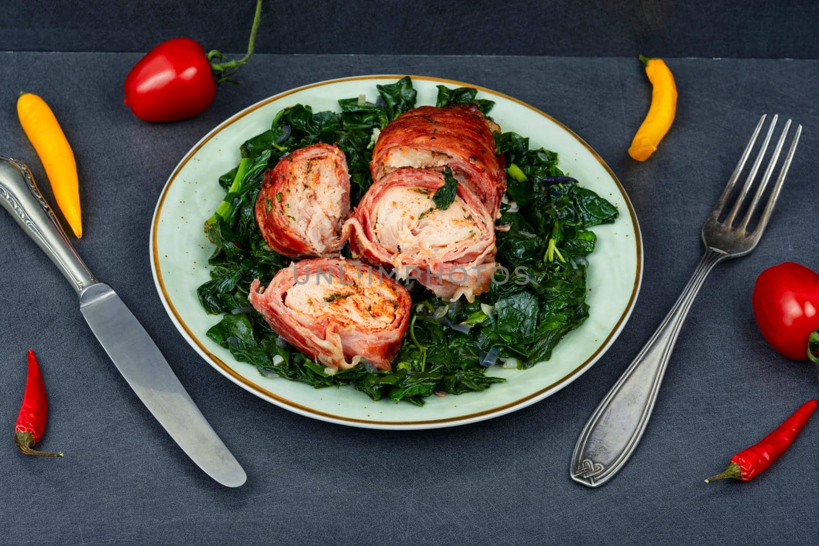 Baked chicken roll with fried spinach leaves. Space for text