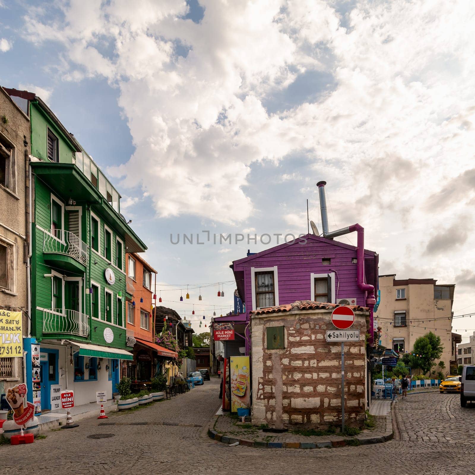 Istanbul, Turkey - August 30, 2022: Cobblestone alley, with beautiful old colorful traditional houses, painted in green, orange and pink, suited in Kapiagasi Street, Fatih district, in a summer day