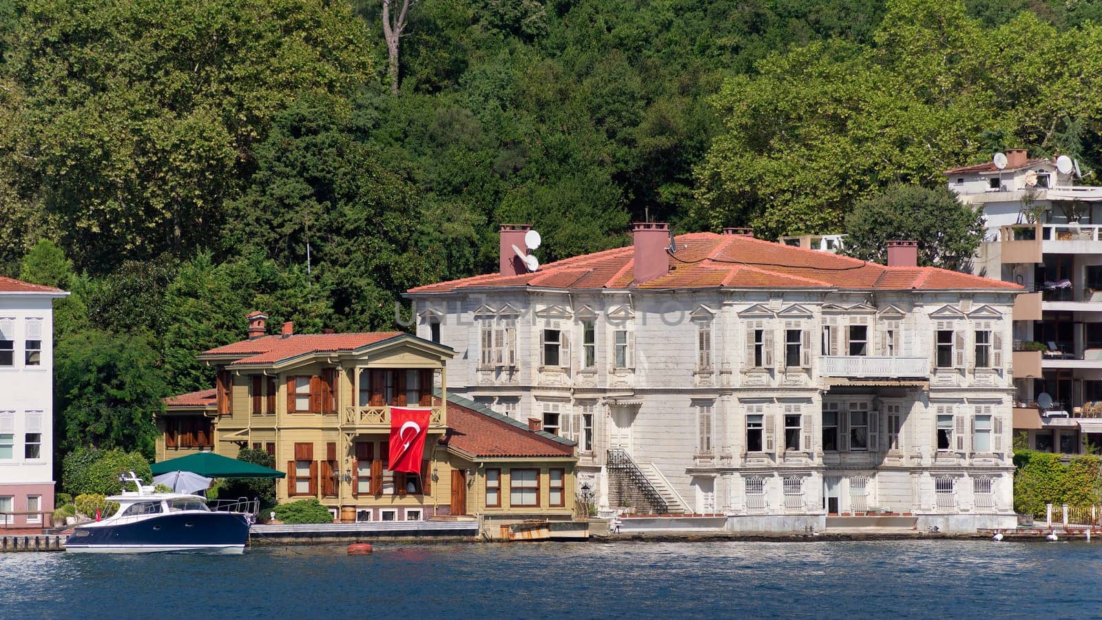 View from Bosphorus strait of the green mountains of the Asian side, with traditional houses and dense trees in a summer day, Istanbul, Turkey
