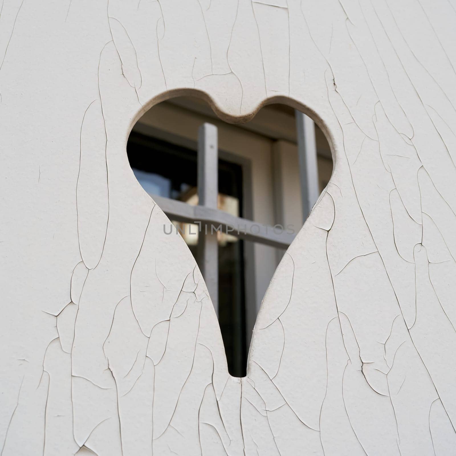 closed white shutter with a heart-shaped opening and cracks in the paint in the old town of Colmar in France