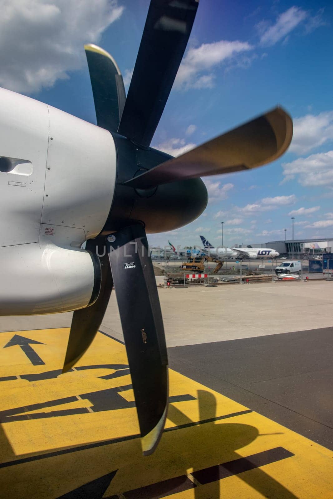 Warsaw, Poland - Jun 30, 2021. View from the window of an aircraft onto a wing to which a propeller engine is attached. The plane is landing at Warsaw Chopin International Airport.