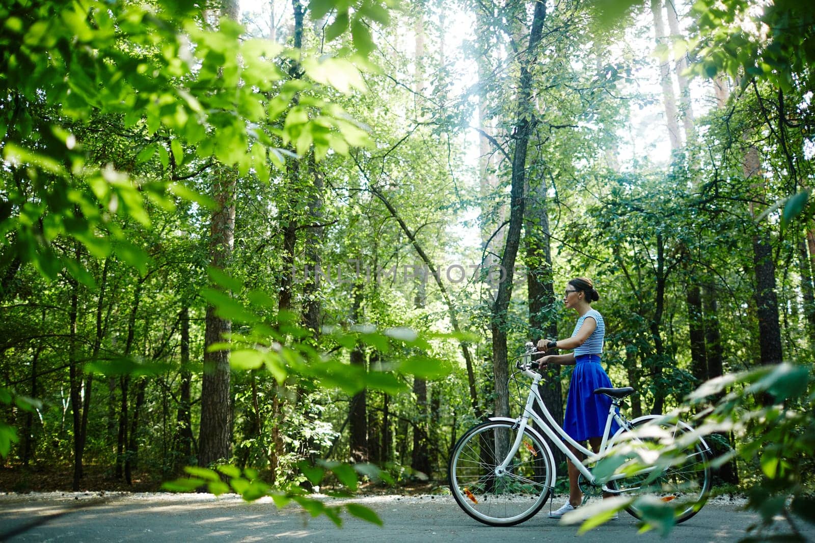 Modern girl with bicycle walking down park