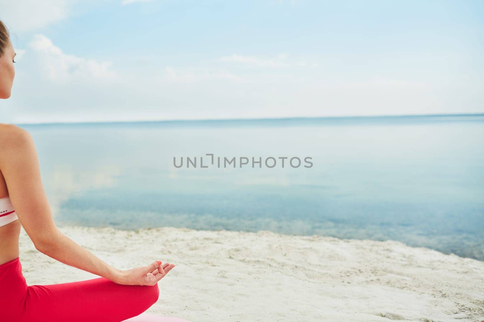 Meditating woman sitting in lotus pose by water