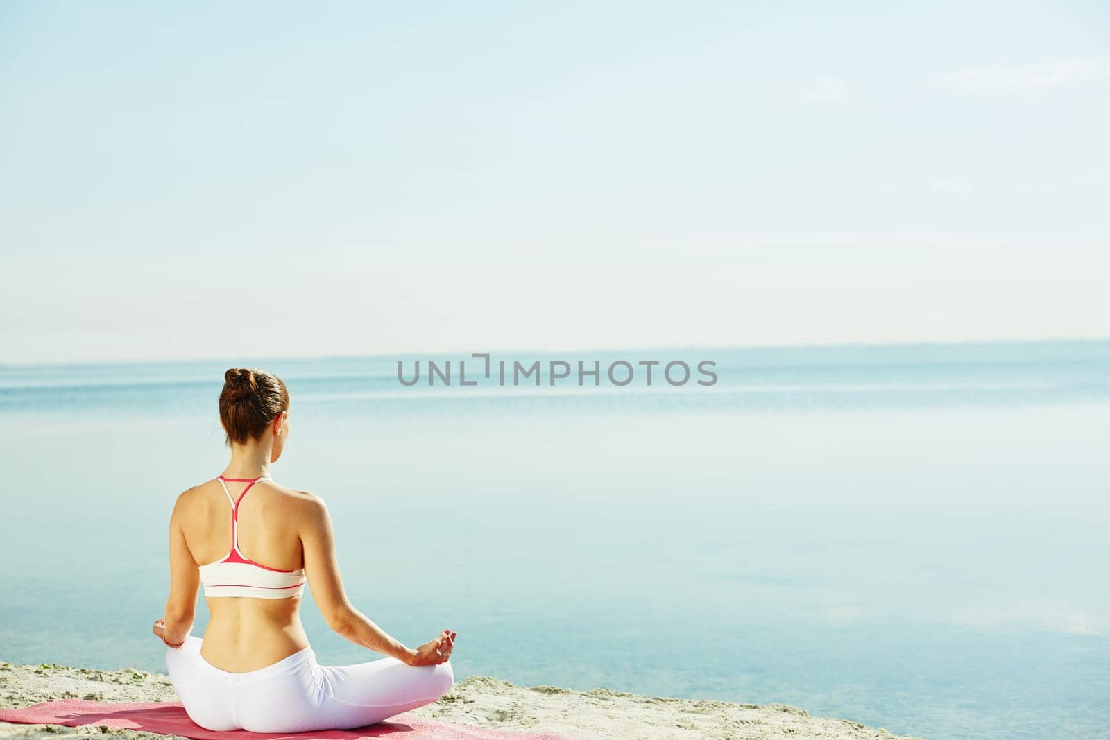 Meditating woman sitting on sandy beach