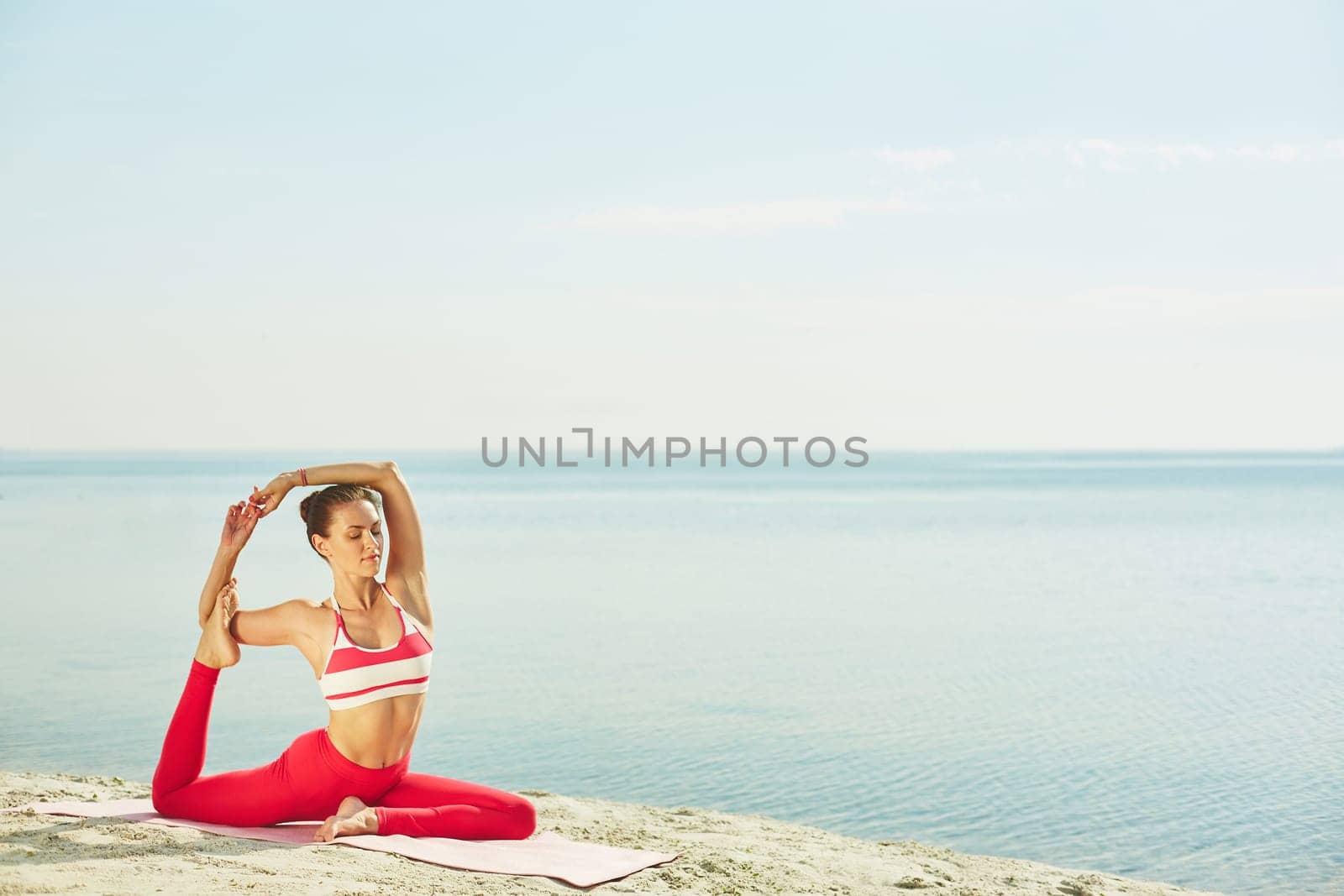 Fit girl doing yoga exercise for balance on sandy beach