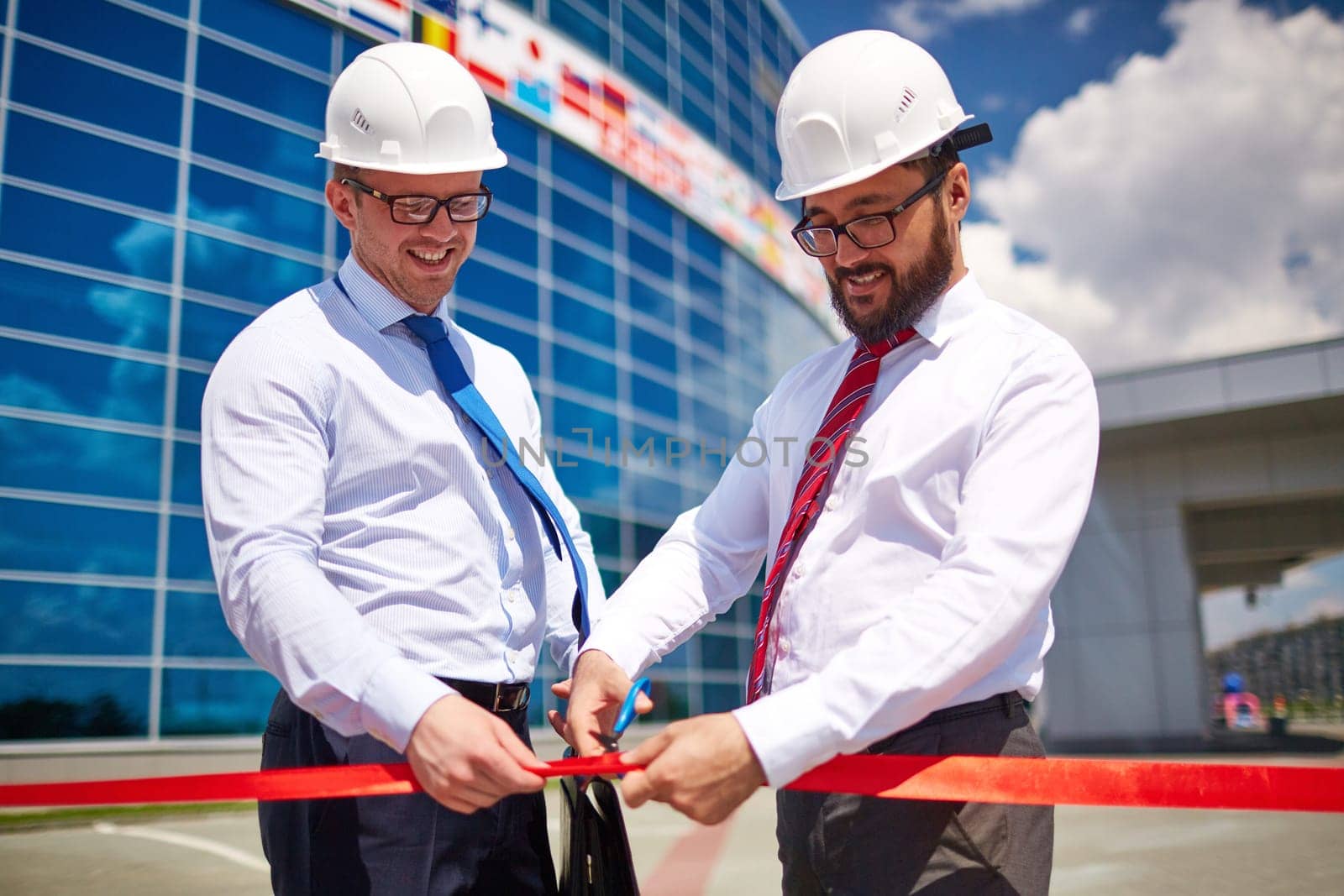 Happy architect cutting red ribbon at official opening of new construction