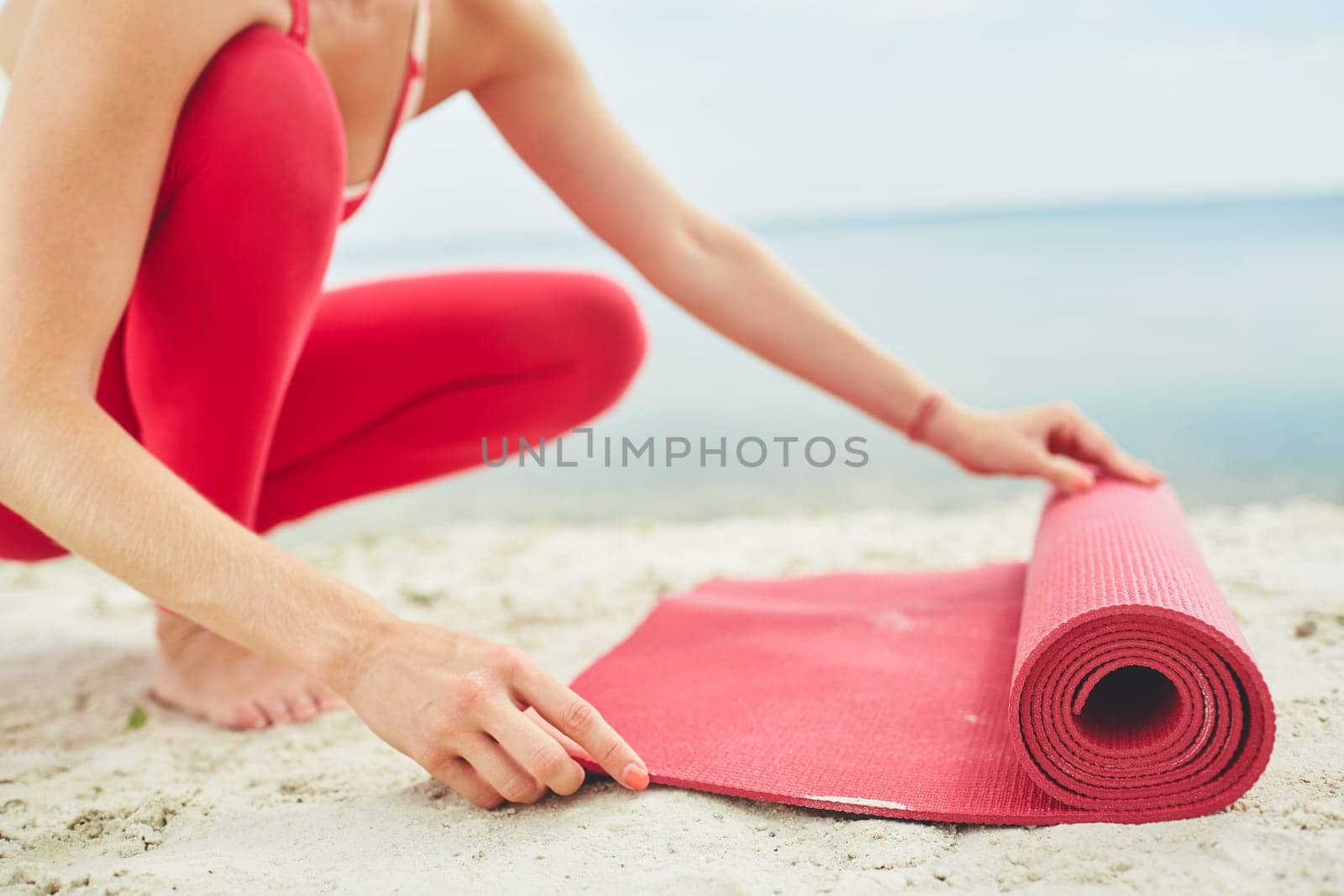 Close-up of young woman unfolding mat for yoga practice