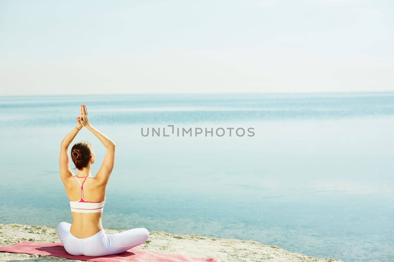 Young woman doing yoga exercise on sandy beach