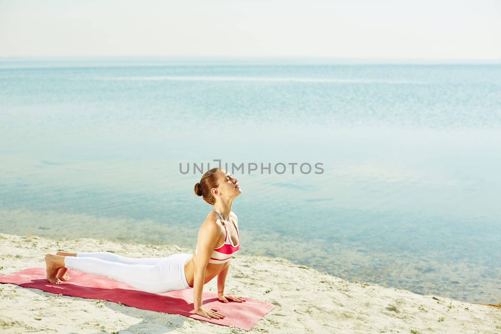 Fit woman doing stretching exercise by the seaside