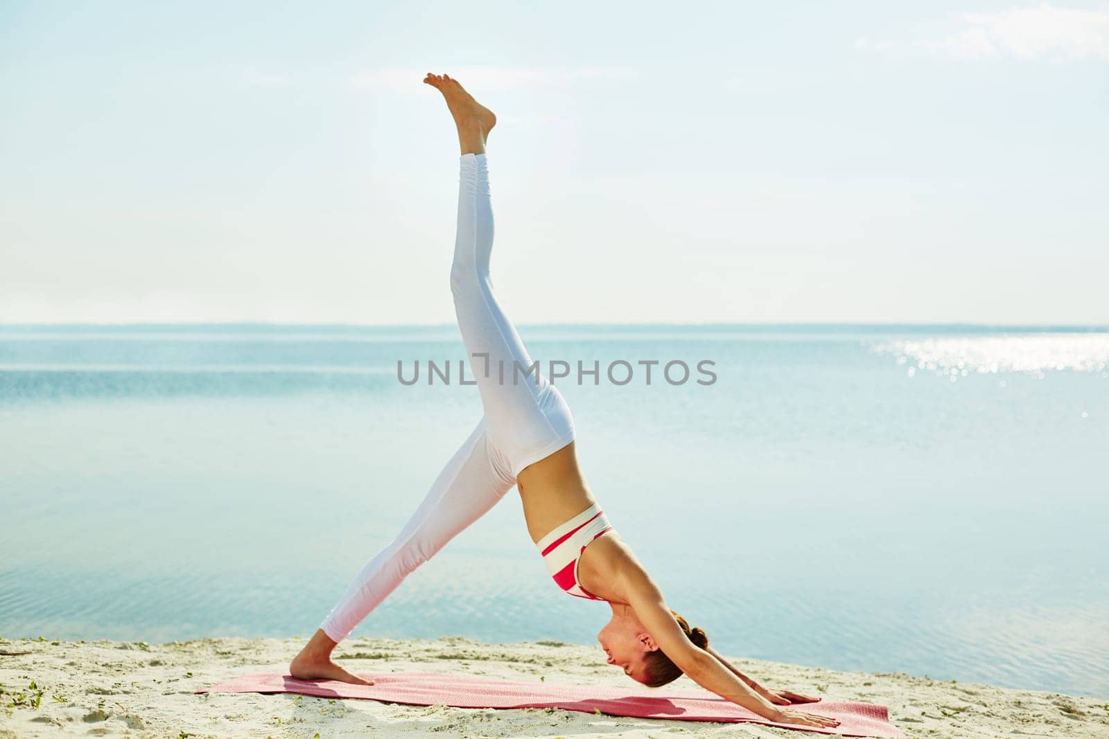Young woman doing yoga exercise by the seaside