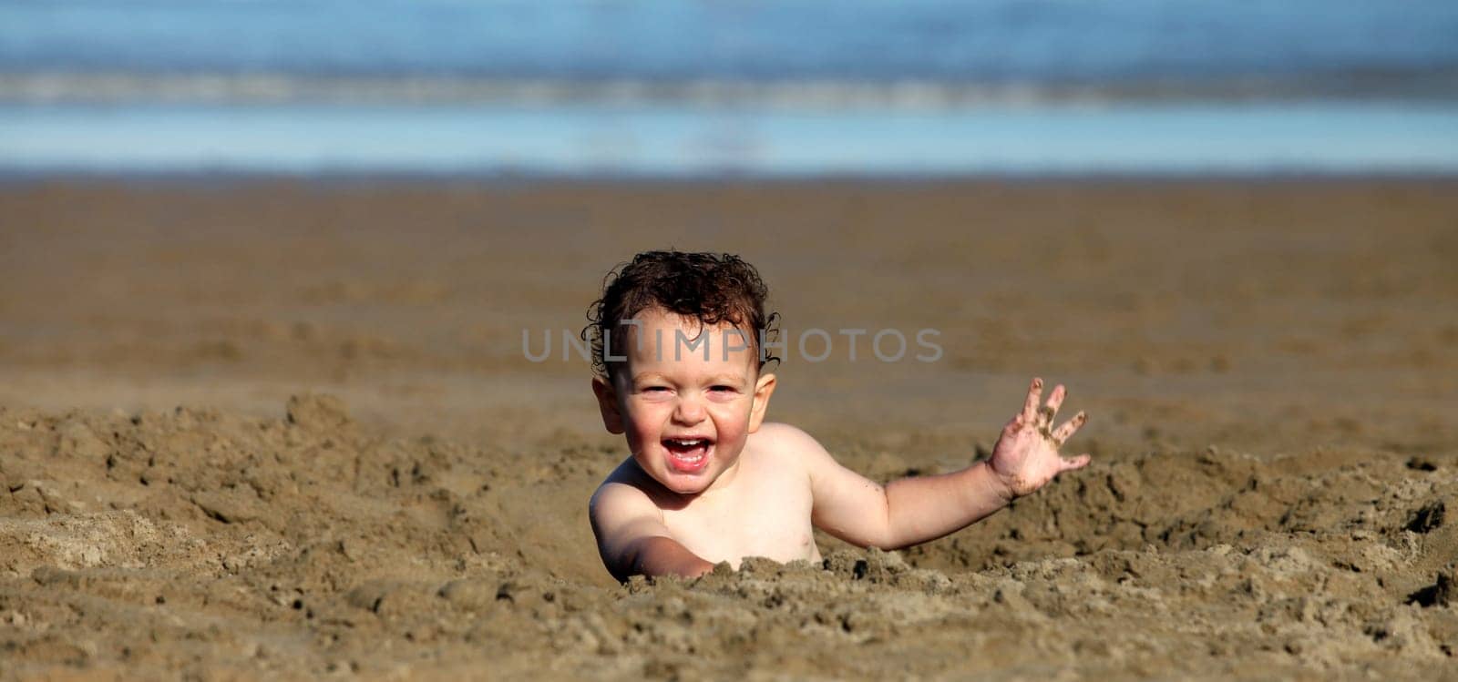 A toddler playing in the sand at the beach.