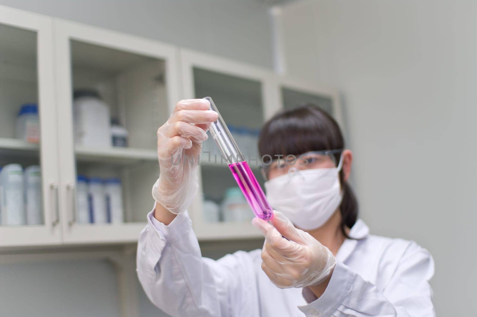 an Asian analyst is observing a chemical tube