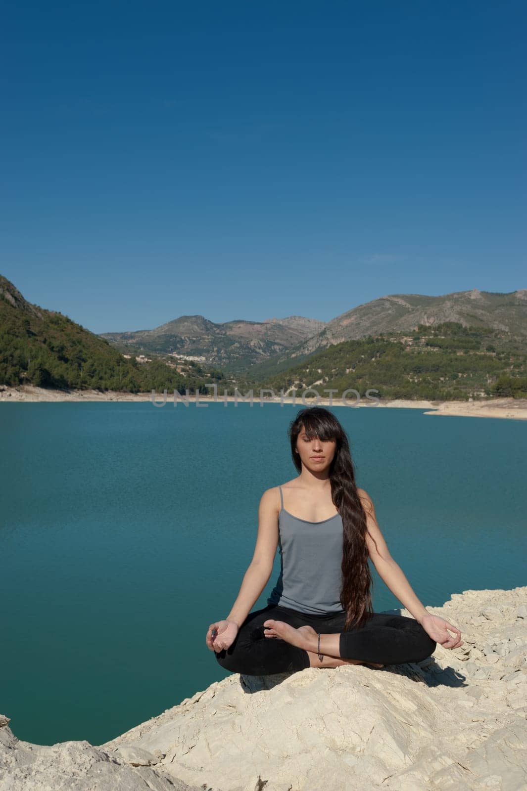 Girl relaxing and doing yoga on the peaceful shores of a lake