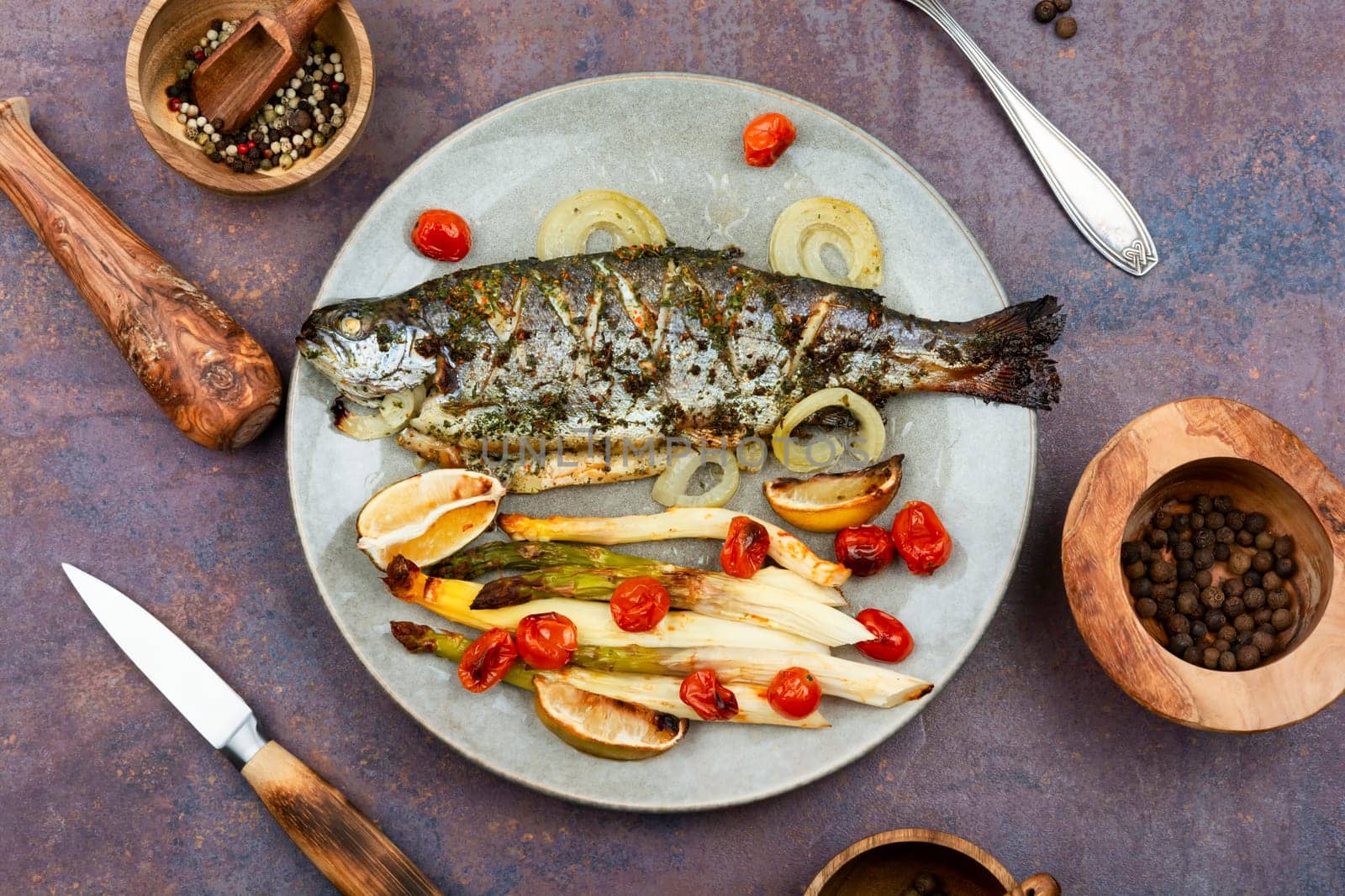 Whole river trout baked with white asparagus and tomatoes. Top view.