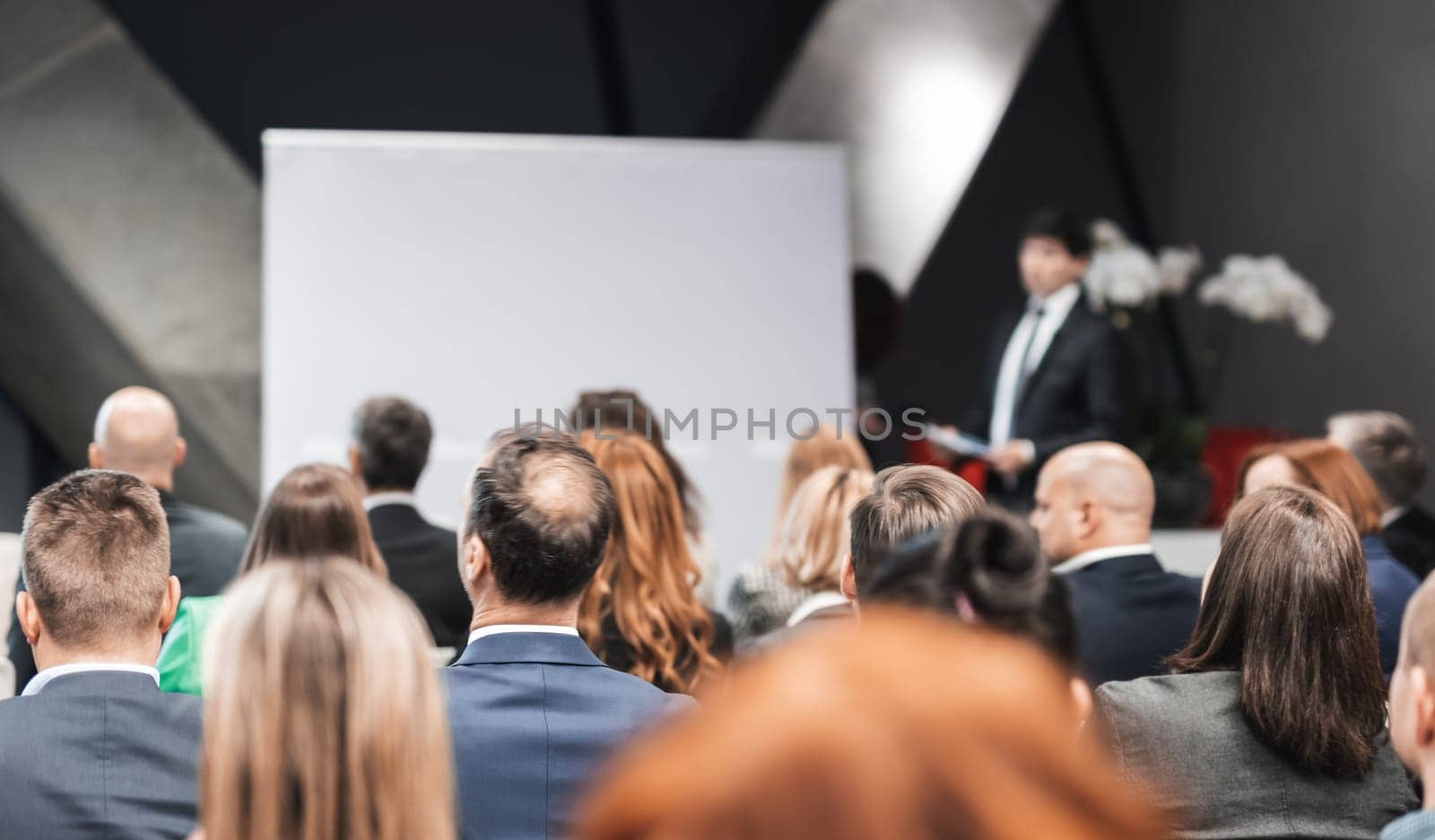 Speaker giving a talk in conference hall at business event. Rear view of unrecognizable people in audience at the conference hall. Business and entrepreneurship concept