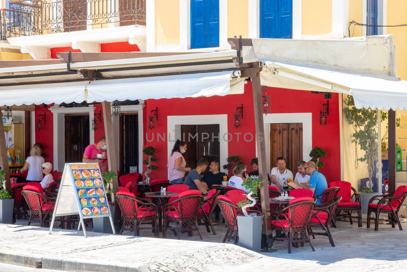 SYMI, Greece - Jun 03, 2021. A restaurant on the harbour promenade of Symi town where tourists linger. Most beautiful and romantic district in the whole Aegean.