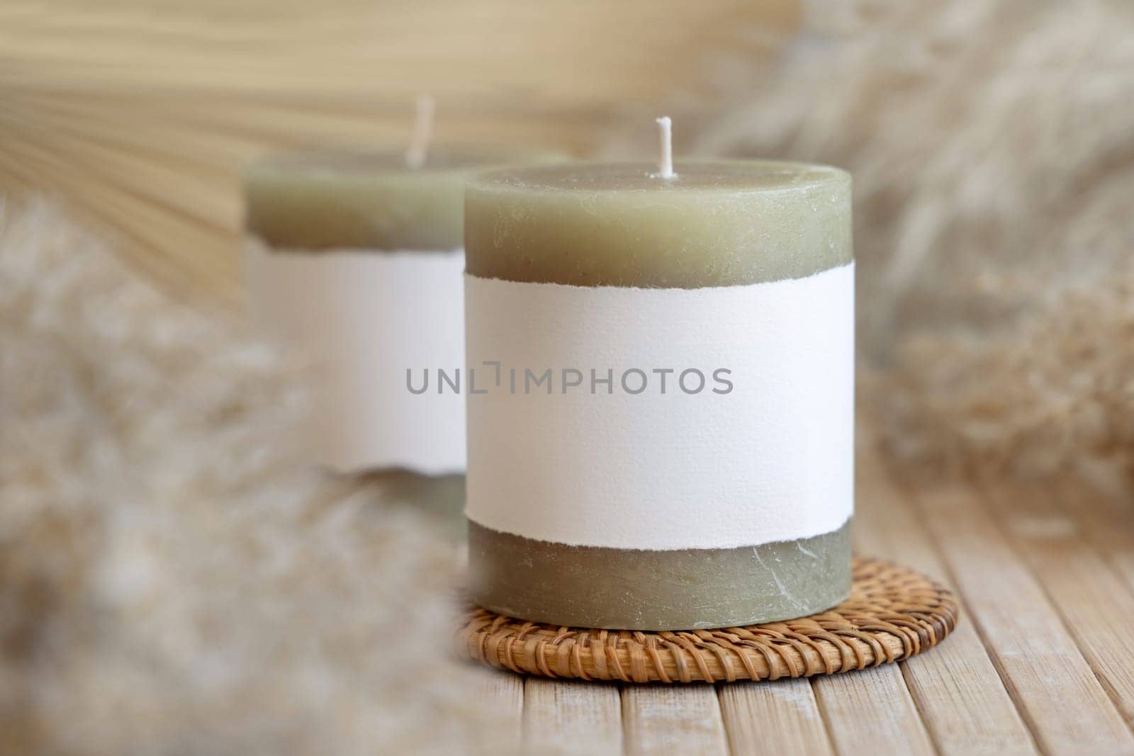 Candles with blank paper label on wooden table with dried pampas grass, Close up, copy space. Minimal brand packaging mock up. Home decoration, minimal interior, Bohemian or scandinavian style..