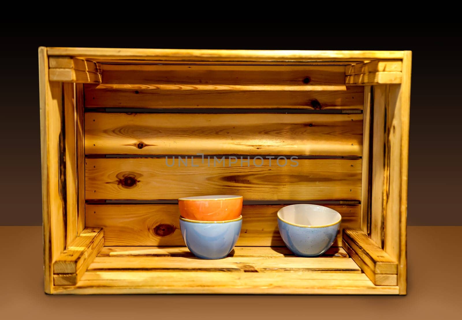 Several ceramic bowls stand very decoratively in a wooden box.
