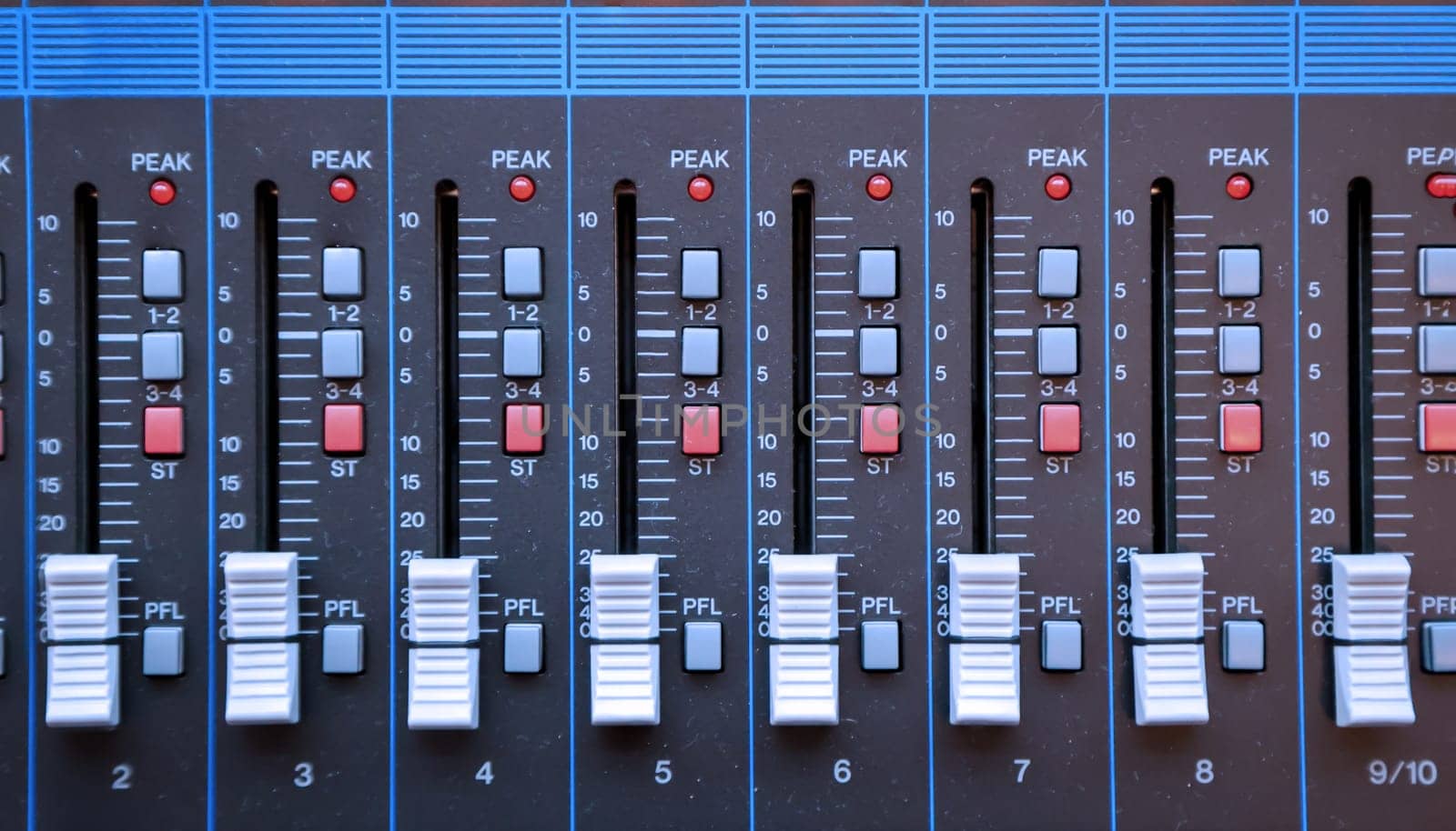 A detailed view of a DJ's mixing desk, knobs and sliders.