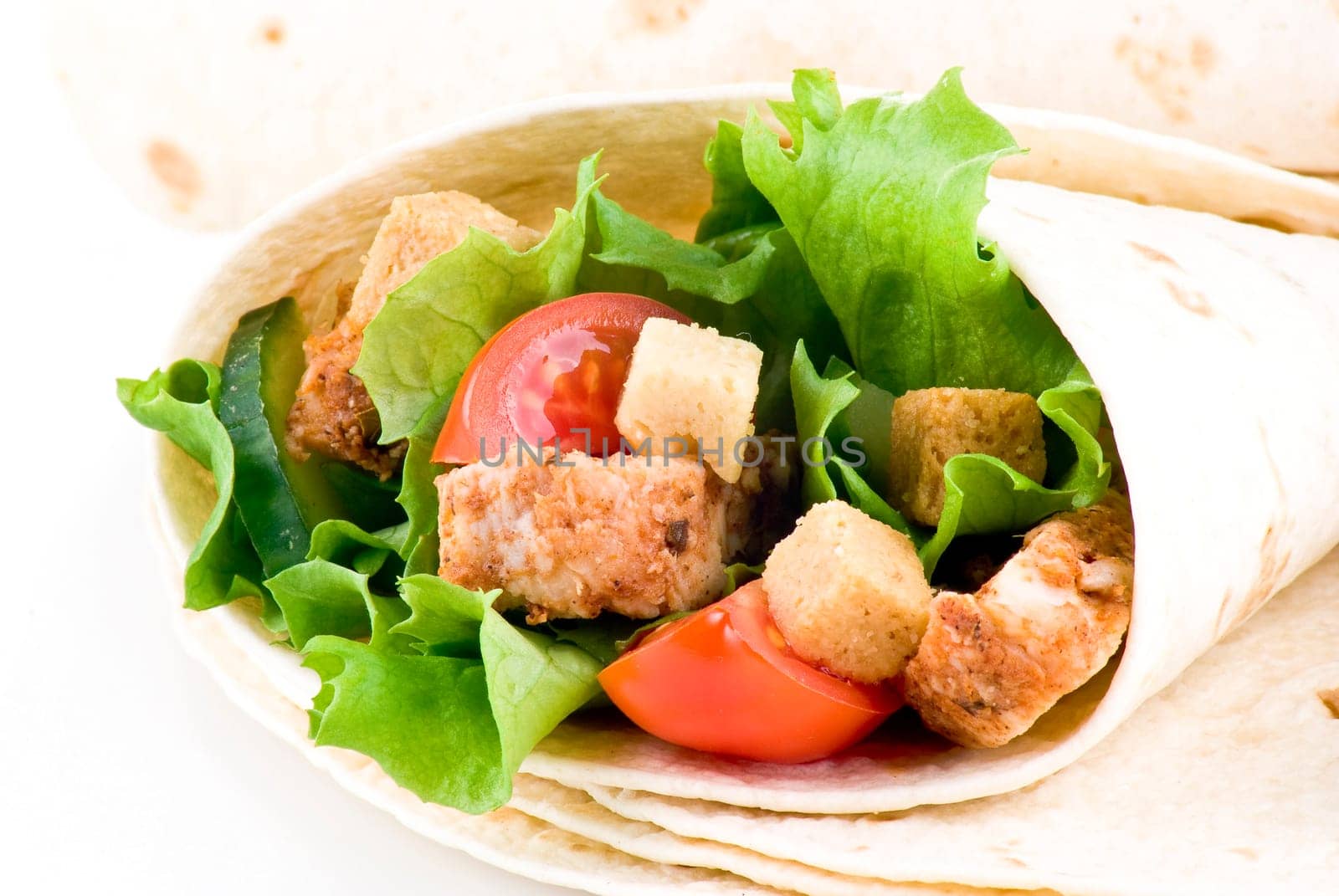 Tortilla filled with lettuce chicken tomatoes and cucumber with plain tortillas