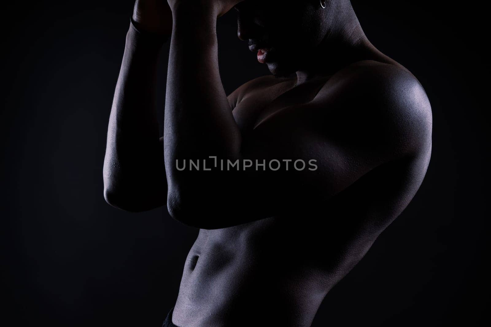 Portrait of athletic african american man topless, black background