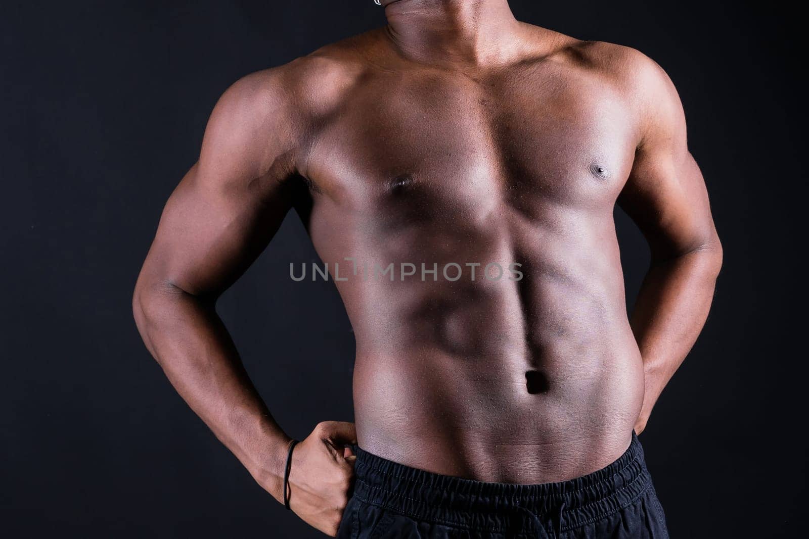 Isolated african muscular man with dumbbells on a dark studio background. Strong shirtless black guy
