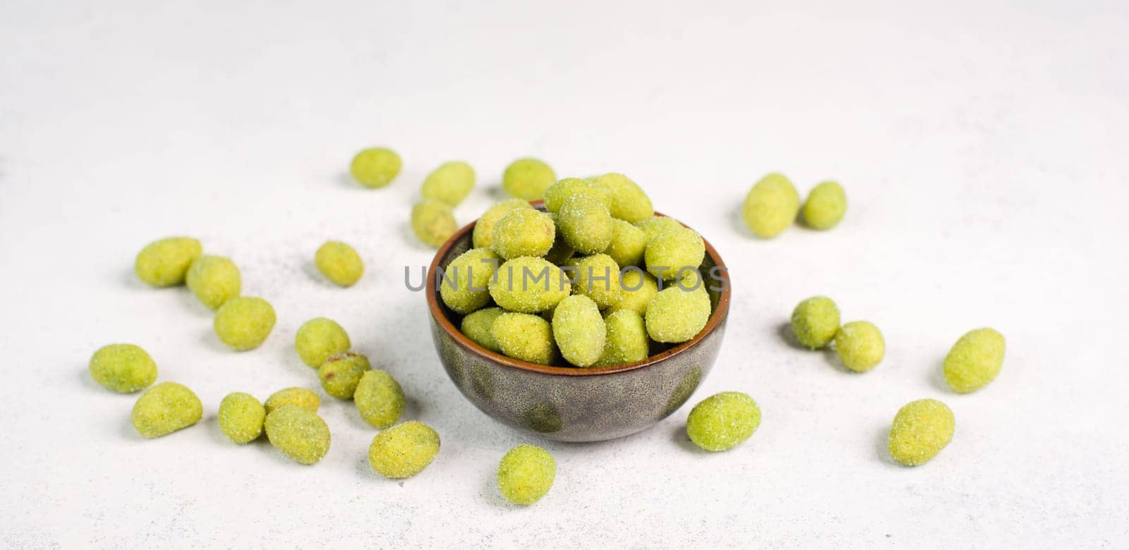 Pile of green wasabi coated peanuts in a bowl, spicy snack, oriental food
