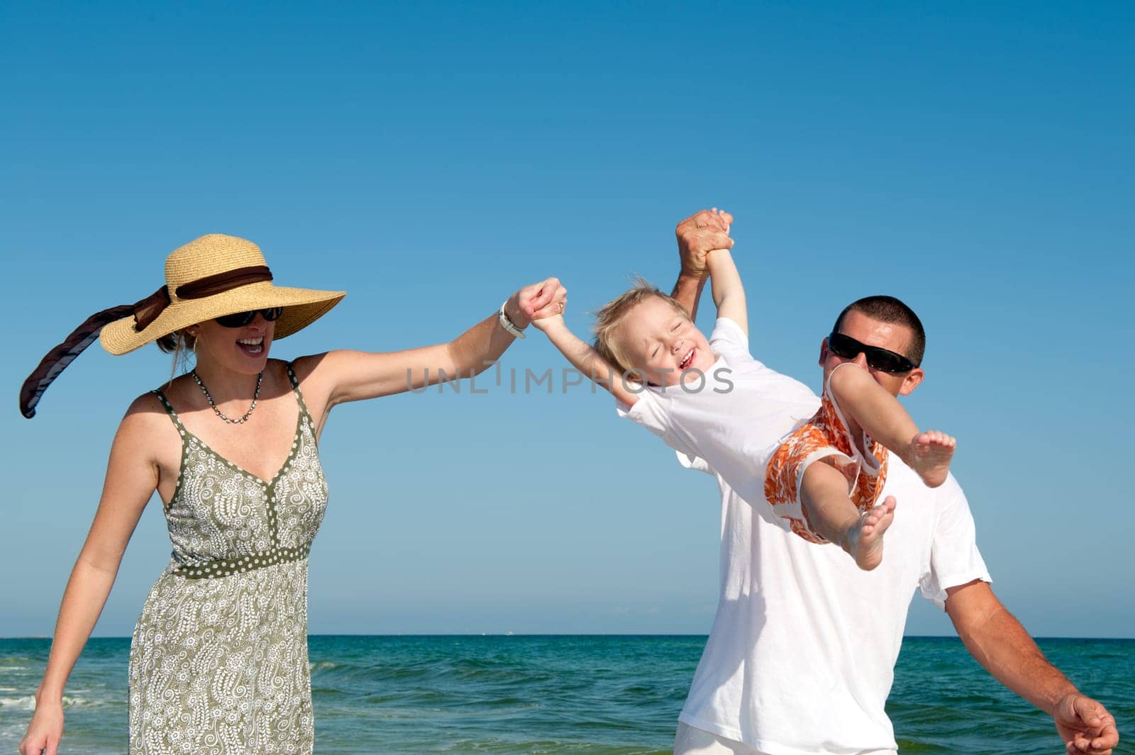 Happy parents and child having fun spending time at the beach