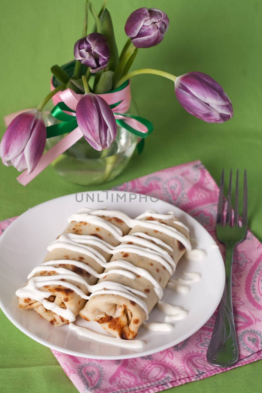 Pancakes with sour cream for breakfast and a vase of purple tulips