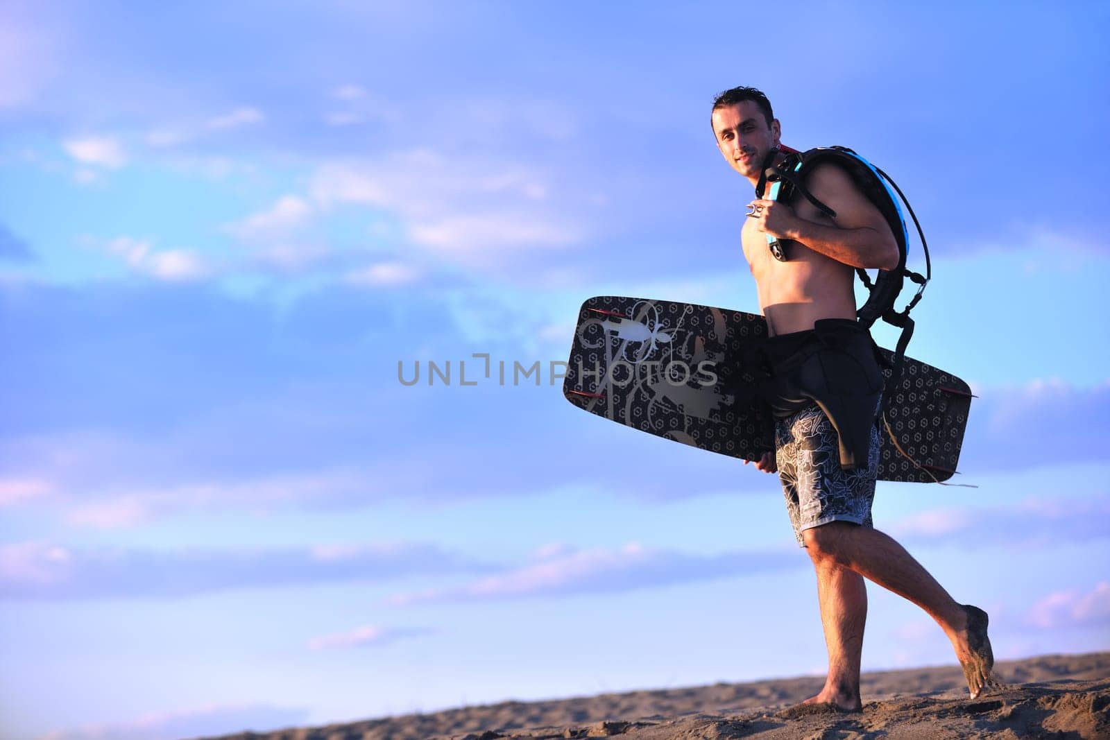 Portrait of a strong young  surf  man at beach on sunset in a contemplative mood with a surfboard