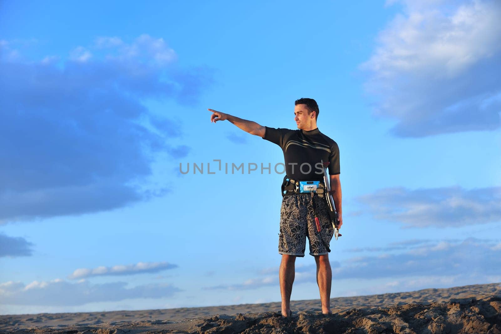 Portrait of a strong young  surf  man at beach on sunset in a contemplative mood with a surfboard