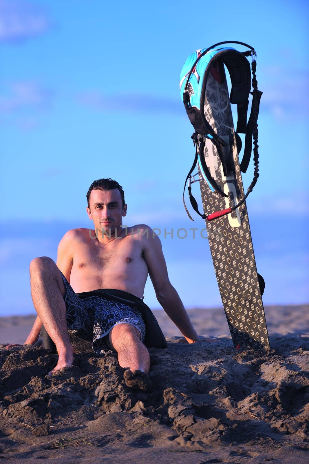 Portrait of a strong young  surf  man at beach on sunset in a contemplative mood with a surfboard
