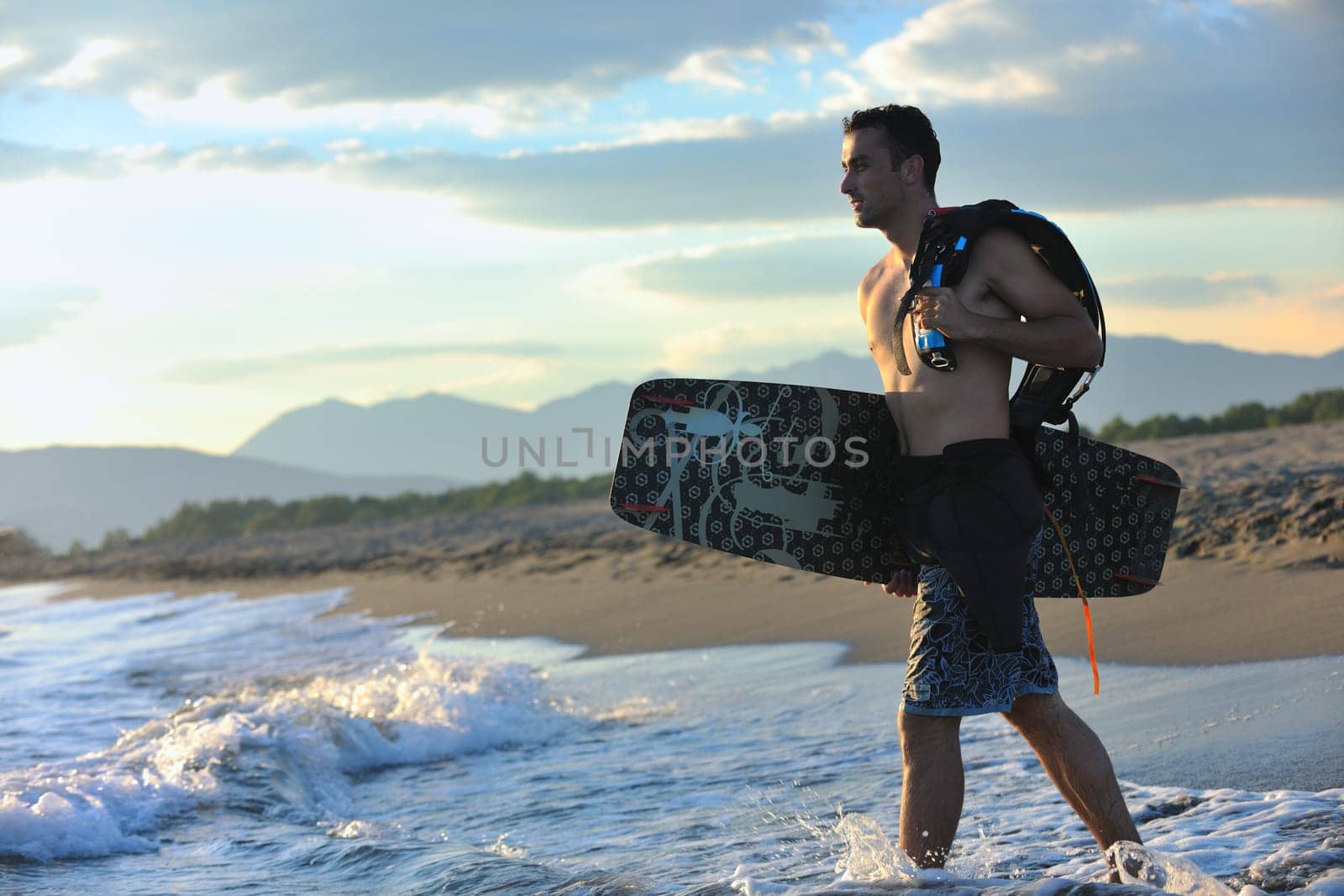 Portrait of a strong young  surf  man at beach on sunset in a contemplative mood with a surfboard