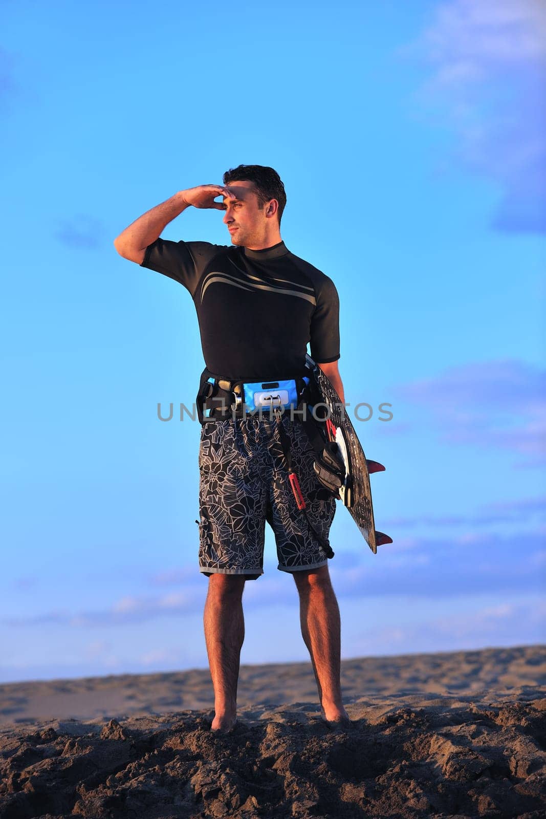 Portrait of a strong young  surf  man at beach on sunset in a contemplative mood with a surfboard