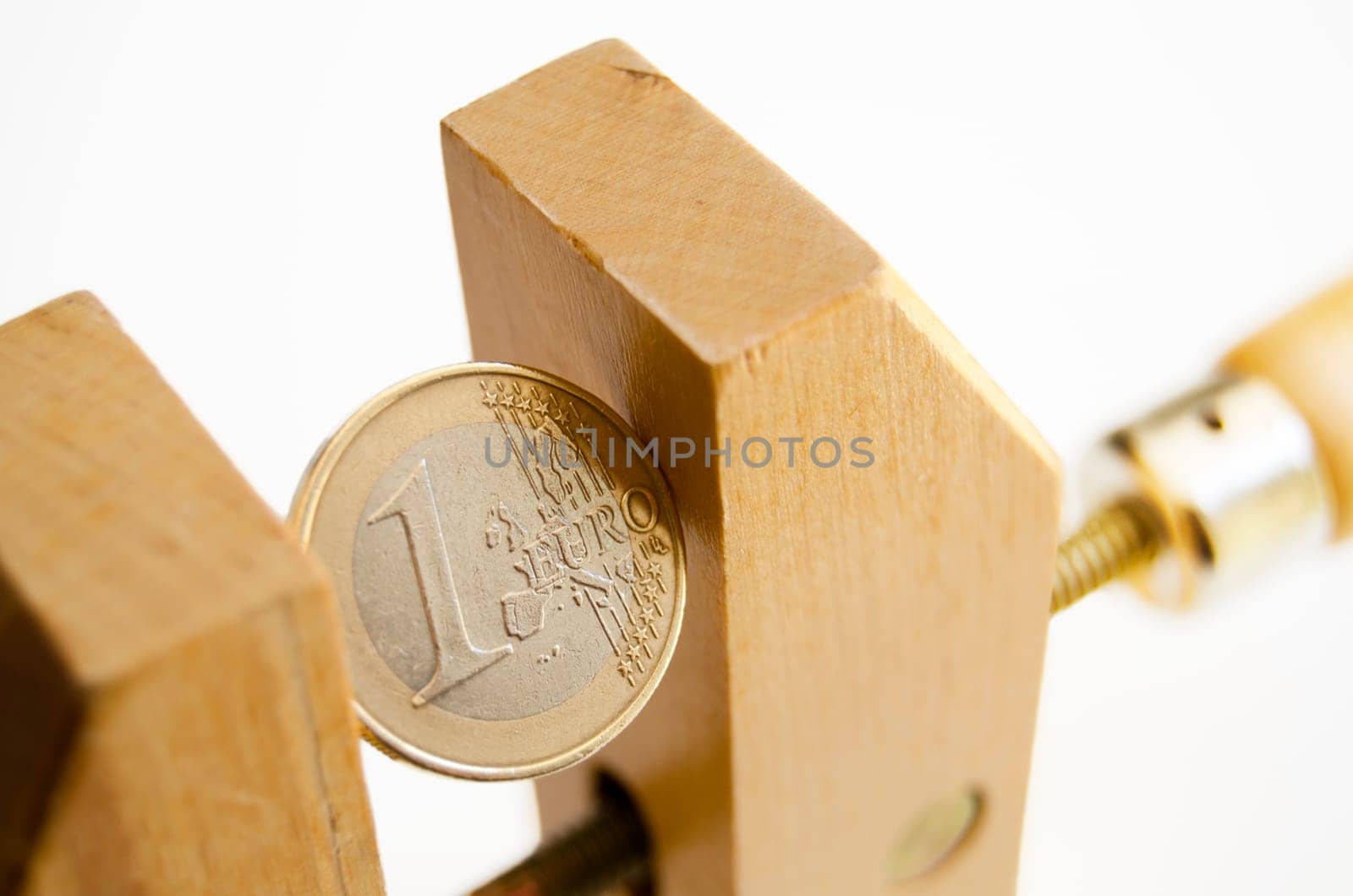 One euro coin under pressure in  a wooden clamp