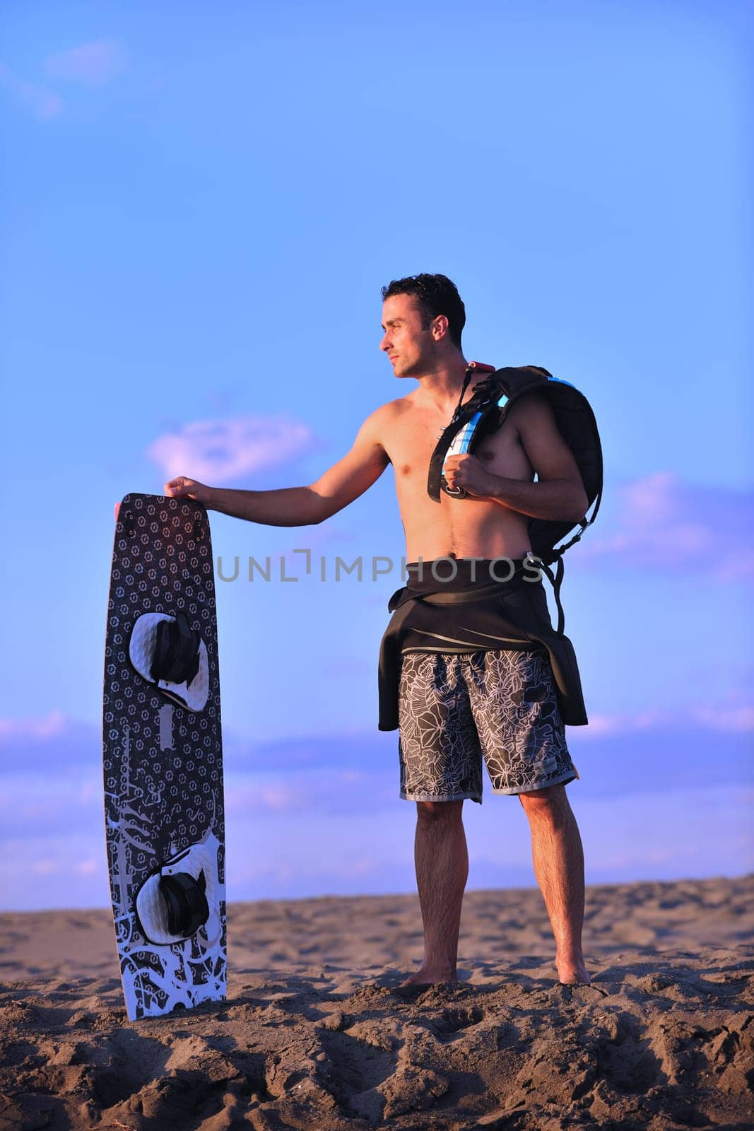 Portrait of a strong young  surf  man at beach on sunset in a contemplative mood with a surfboard