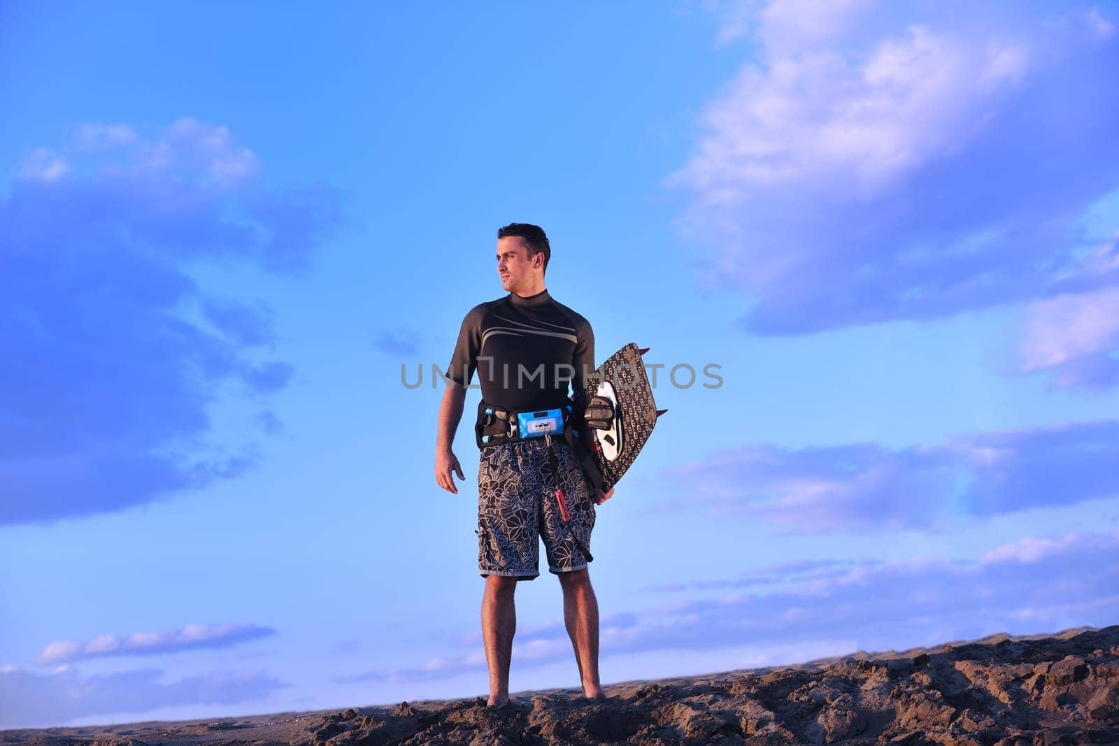 Portrait of a strong young  surf  man at beach on sunset in a contemplative mood with a surfboard