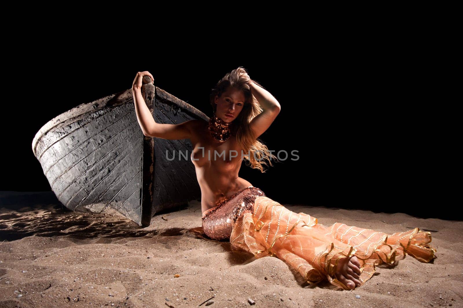 woman in exotic dress standing on a boat on the beach
