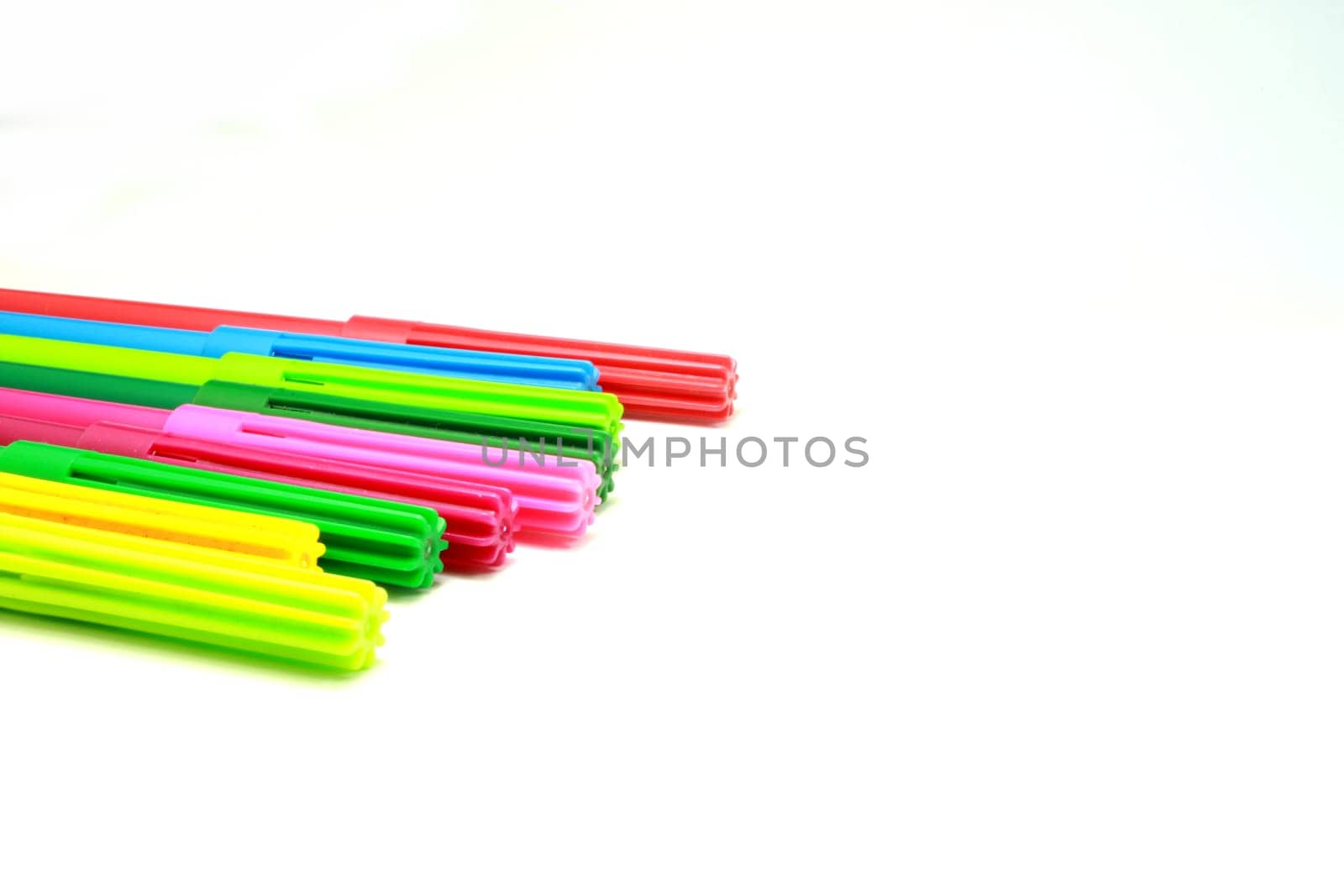 A few colourful pens agaist a white background . Maybe used to signify art , vibrancy , colour or anything creative.